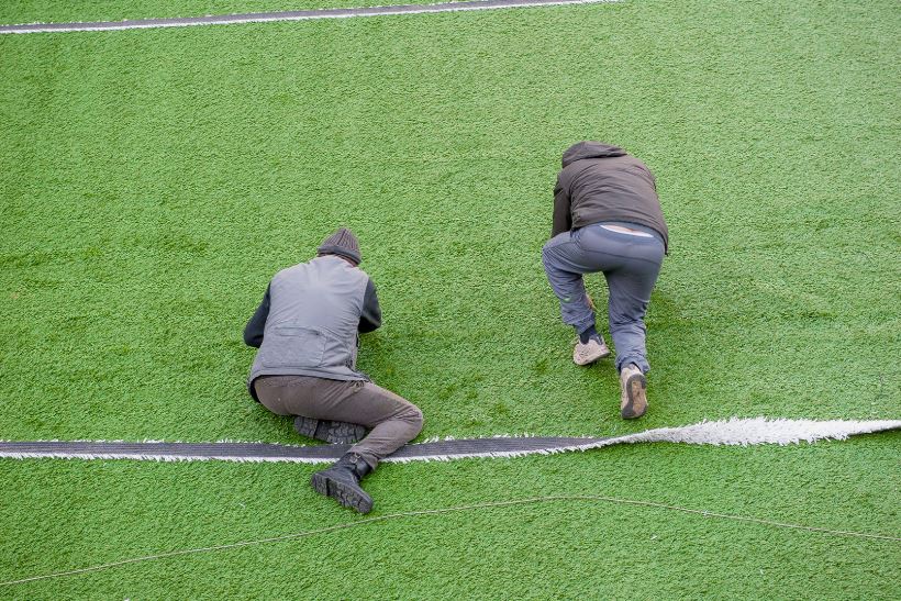 deux hommes pose du gazon synthetique sur une dalle beton